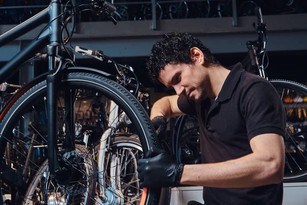 Diligente joven mecánico está reparando clientes bicicleta en el lugar de trabajo — Foto de Stock