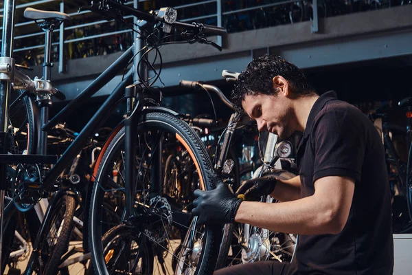 Diligente joven mecánico está reparando clientes bicicleta en el lugar de trabajo — Foto de Stock