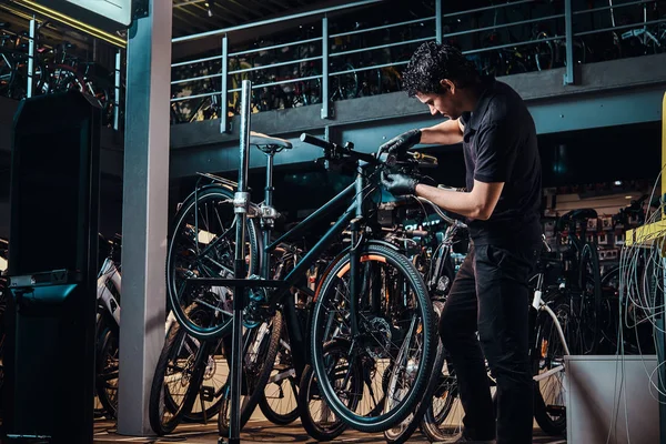 Expirienced joven maestro está reparando clientes bicicleta en el lugar de trabajo — Foto de Stock