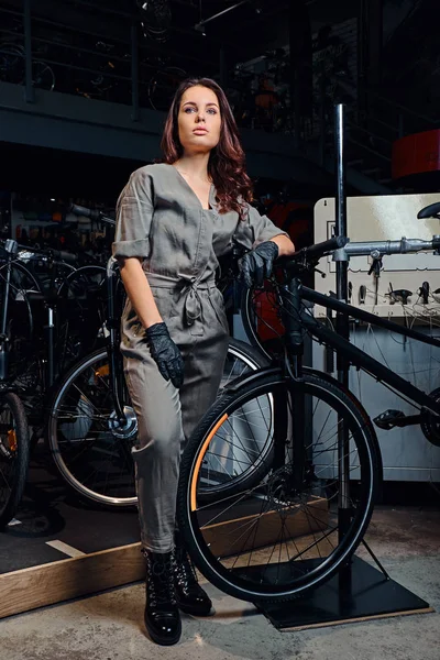 Trabalhador apperentice atraente está posando com bicicleta na oficina — Fotografia de Stock