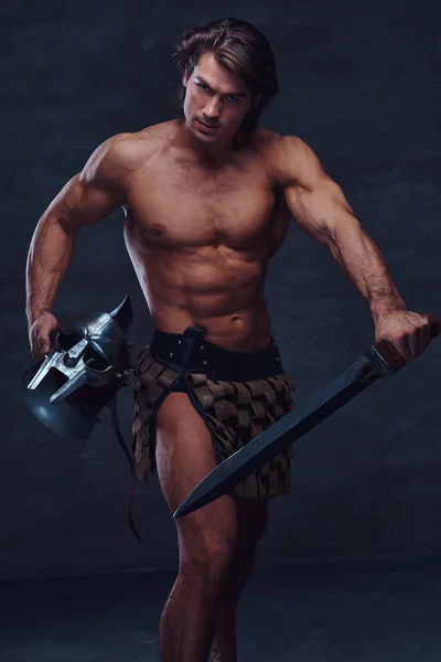 Muscular man with sword and helmet is lookig to the camera