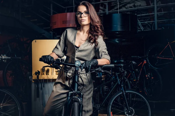 Diligent attractive woman is trying fixed bicycle at busy workshop
