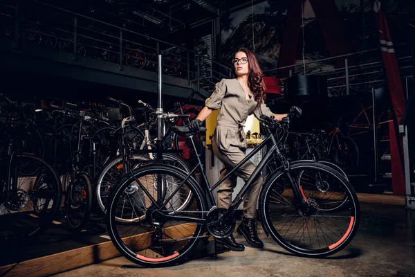 Diligent attractive woman is trying fixed bicycle at busy workshop