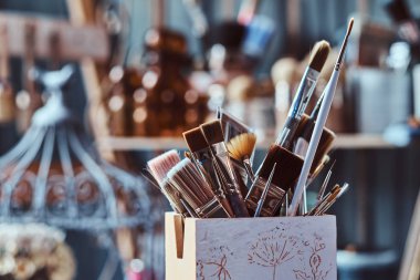 Sanat stüdyosunda masada farklı fırçalar ile Kavanoz