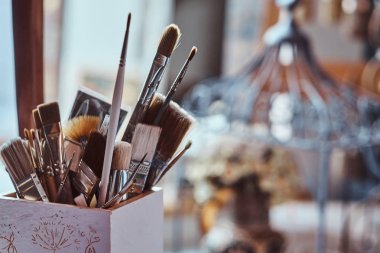 Sanat stüdyosunda masada farklı fırçalar ile Kavanoz