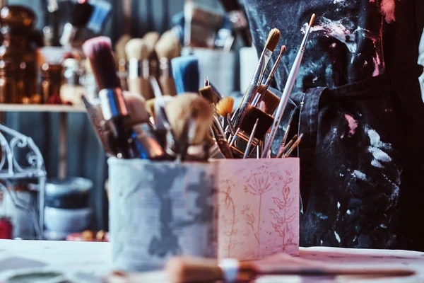 Escovas e frascos em estúdio de artistas na mesa — Fotografia de Stock