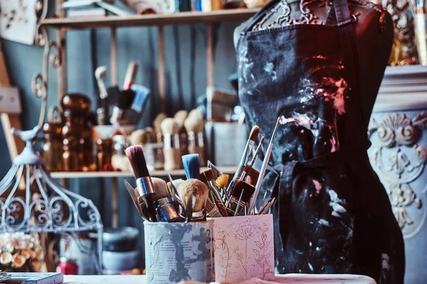 Кисти и банки в мастерской художников на столе с манекеном . — стоковое фото