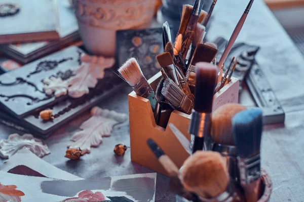 Viele verschiedene Pinsel auf dem Künstlertisch in Gläsern. Artilleriefeuer auf dem Tisch — Stockfoto
