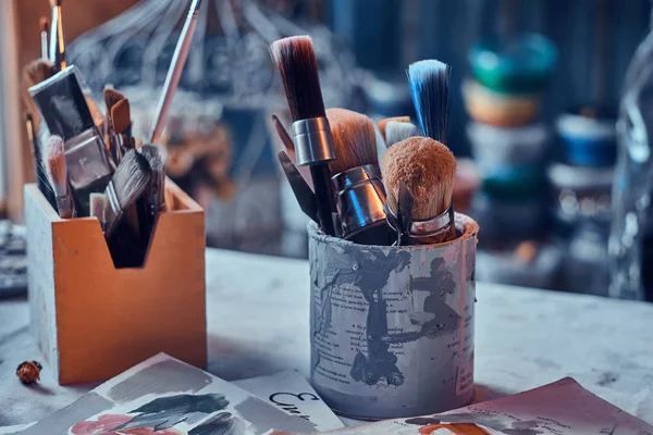 Muitos pincéis diferentes na mesa de artistas em jarros. Há artisticks bagunça na mesa — Fotografia de Stock