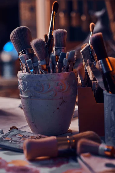 Kavanozlarda sanatçı masasında bir sürü farklı fırça. Masada artistikler var.. — Stok fotoğraf