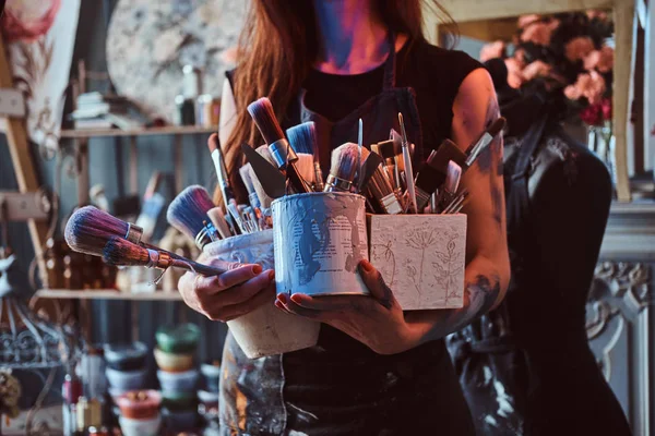 Talentosa pintora está posando com pincéis em seu próprio estúdio de arte . — Fotografia de Stock