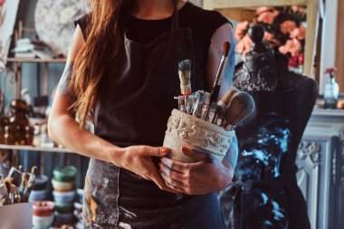 Genç ressam kendi stüdyosunda uzun bir çalışma gününden sonra ortalığı toparlıyor.