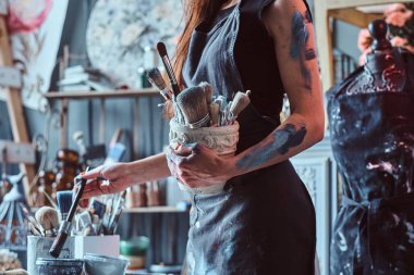 Atölyede yetenekli sanatçı fırçalar ile kavanoz tutarken yeni projesi için boya karıştırma