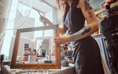 Genç yetenekli ressam eski çerçeveyi kendi atölyesinde yeniden düzenliyor.
