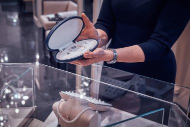 Zarif kuyumcu lar yardımcısı müşteri için durumda güzel inci kolye gösteriyor