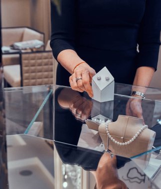 Zarif kuyumcu yardımcısı müşteri için beatiful inci küpe gösteriyor