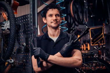 Genç çekici tamirci kendi atölyesinde bisikletinin yanında poz veriyor.