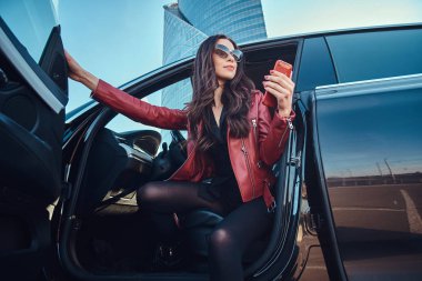 Güzel akıllı kadın cep telefonu sohbet ederken onu yeni arabada poz