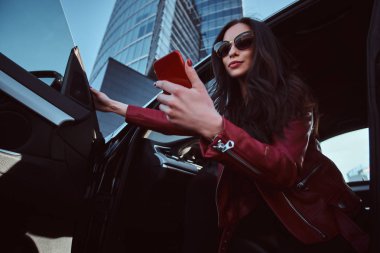 Güzel akıllı kadın cep telefonu sohbet ederken onu yeni arabada poz