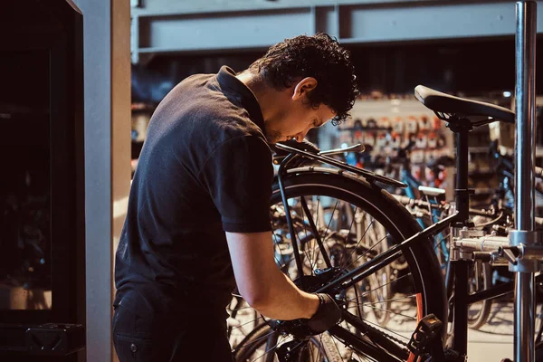 Attractive mechanic is fixing customers bicycle at his own workshop.