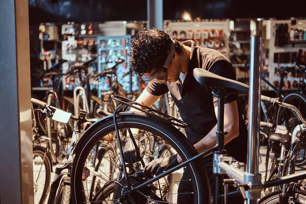 Заботливый мастер в защитных очках чинит велосипед в мастерской — стоковое фото