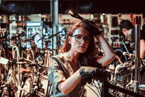 Junge attraktive Arbeiterin chillt nach Reparatur von Kundenfahrrad in Werkstatt — Stockfoto