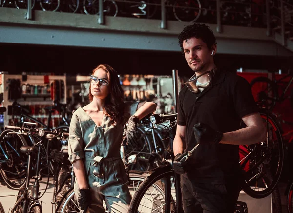 Joven maestro y su atractivo aprendiz están tomando un descanso después de reparar una bicicleta en el taller — Foto de Stock