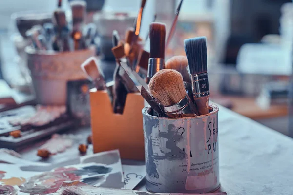 Muitos pincéis diferentes na mesa de artistas em jarros. Há artisticks bagunça na mesa — Fotografia de Stock