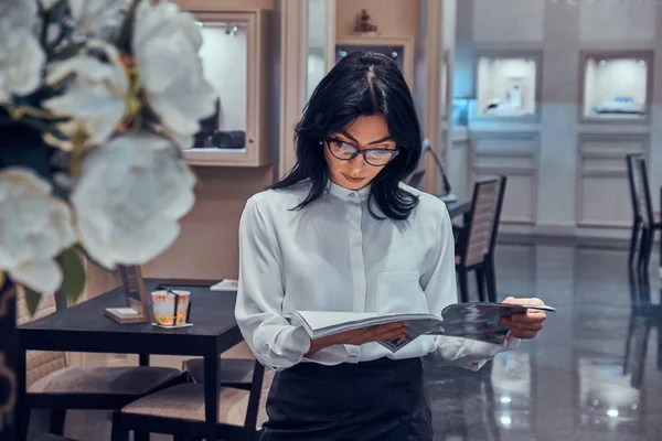 Mulher elegante atraente está assistindo revista na boutique de jóias elegante — Fotografia de Stock