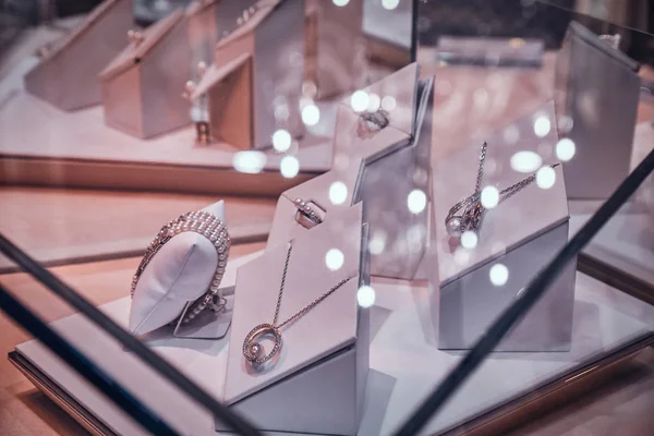 Różnorodność pięknych ozdabiań złota na białym wyświetlaczu pod szkłem w sklepie jubilerskiej — Zdjęcie stockowe