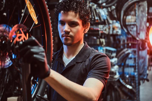 Прилежный мастер чинит велосипедное колесо на своем рабочем месте. — стоковое фото