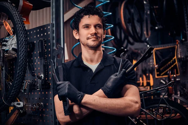 Genç çekici tamirci kendi atölyesinde bisikletinin yanında poz veriyor.