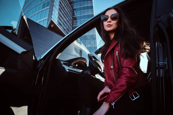 Giovani donne attraenti è in posa nella sua nuova auto. Lei indossa giacca rossa e occhiali da sole — Foto Stock
