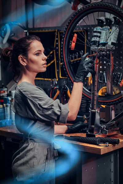 Çalışkan güzel kız pnömatik teller arasında yoğun atölyesinde bisiklet tamir ediyor