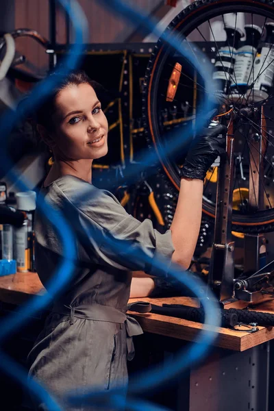 Çalışkan güzel kız pnömatik teller arasında yoğun atölyesinde bisiklet tamir ediyor