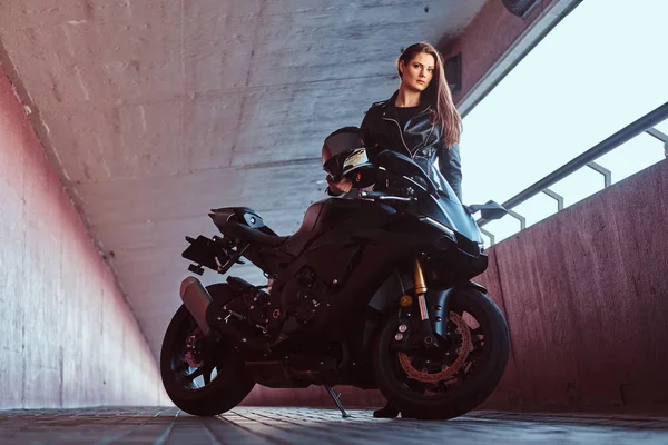 Genç ve çekici bir kadın bisiklet ve kaskıyla tünelde dikiliyor.