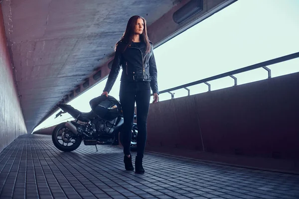 Bella donna pensierosa è in piedi in galleria con la sua moto e casco — Foto Stock