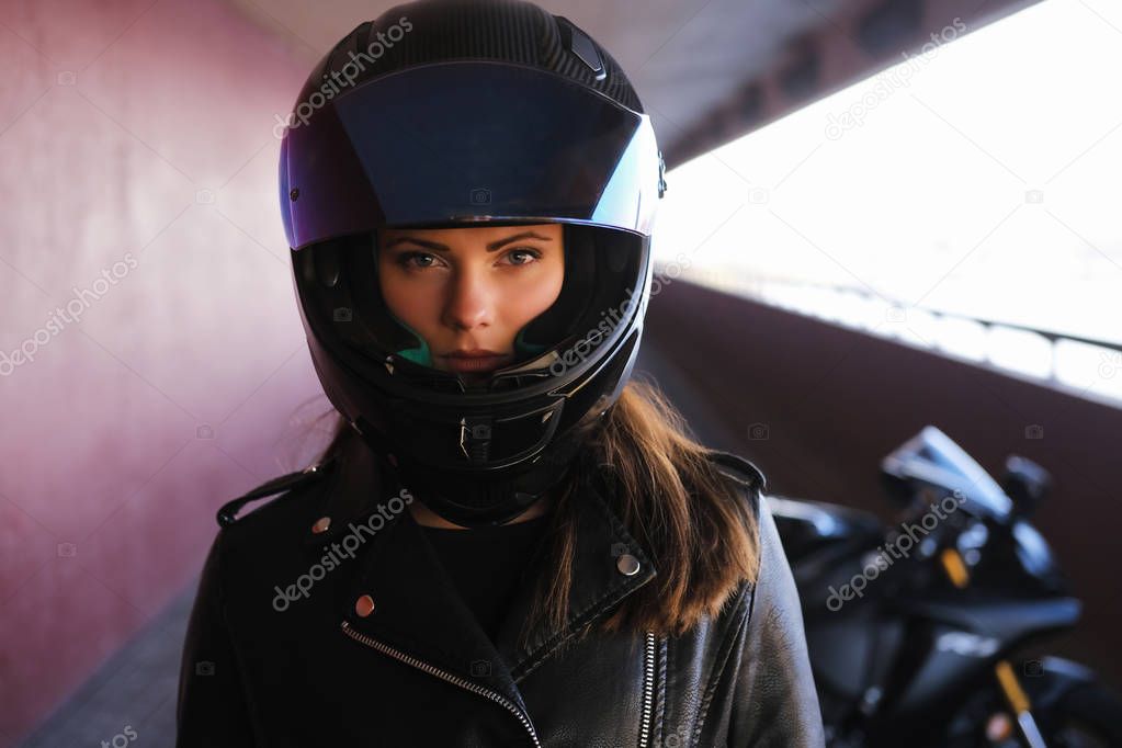 Attractive serious woman is standing next to her motobike