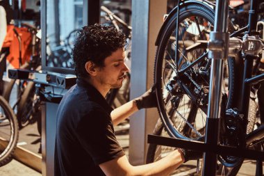 Çekici mekanik kendi atölyesinde müşterilerine bisiklet sabitleme.