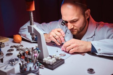 Expirienced saatçi onun atölyesinde custmers izlemek için gravür yapıyor
