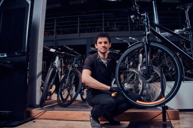 Genç düşünceli usta atölyesinde yorucu bir günün ardından bisikletinin yanında dinleniyor.