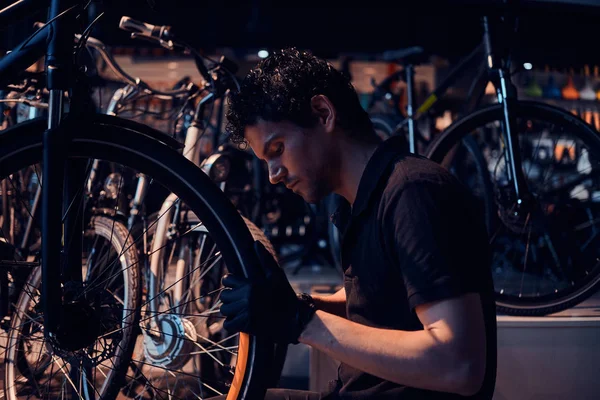 Усердный привлекательный механик ремонтирует велосипеды клиентов на рабочем месте — стоковое фото