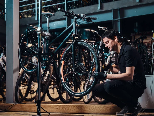 Просроченный молодой мастер ремонтирует клиентам велосипеды на рабочем месте — стоковое фото