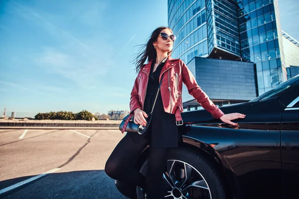 Молода приваблива жінка охолоджується в яскравий сонячний день поруч зі своєю машиною — стокове фото