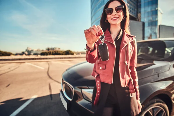Feliz mujer sonriente sosteniendo la llave para el coche, que es ocultar su — Foto de Stock