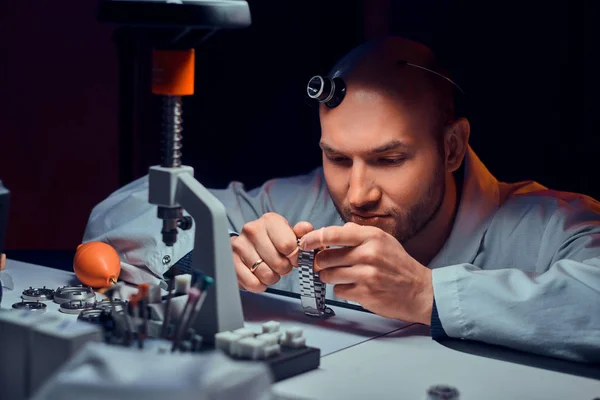 Expirienced watchmaker is doing engraving for custmers watch at his workshop — Stock Photo, Image