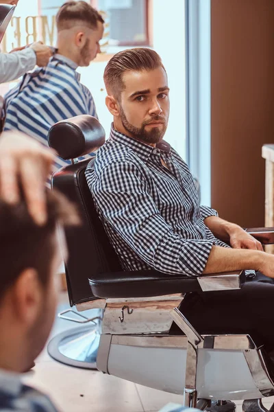 Attraktiver, nachdenklicher Mann wartet beim geschäftigen Friseur darauf, dass er an der Reihe ist — Stockfoto