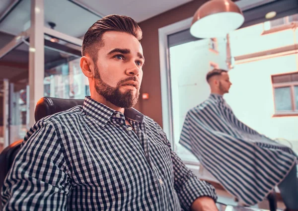 Verzorgde knappe man wacht op zijn beurt om een kapsel te krijgen bij drukke Barbershop — Stockfoto