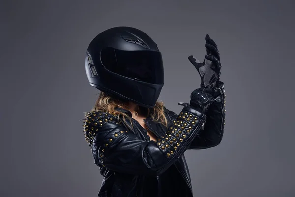 Mode, sport, extrême. Portrait d'une fille motard portant un costume de coureur en cuir et un casque de protection portant des gants dans un studio sur un fond gris . — Photo