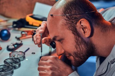 Olgun clockmaster onun meşgul tamir atölyesinde bir müşteri için eski saat sabitleme